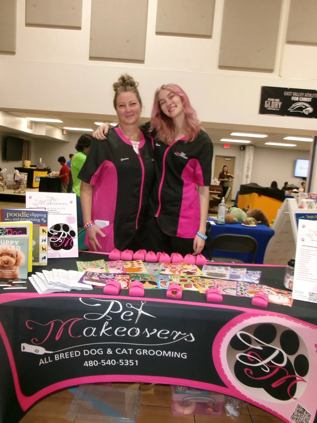Dorine and Rayne from Pet Makeovers smiling at their community event booth